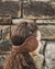 Nordvek adults sheepskin earmuffs 513-100 chocolate model wearing in front of stone wall