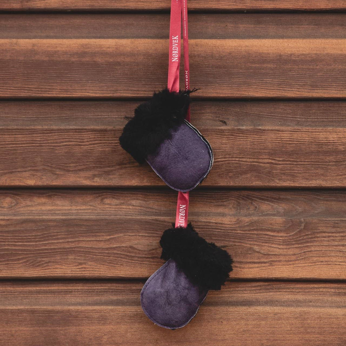 Kids Nordvek sheepskin puddy mittens 303-100 blue with red ribbon hanging on stables