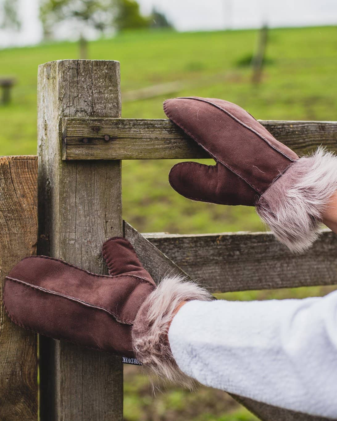 Nordvek womens sheepskin mittens chocolate colour opening wooden gate in field