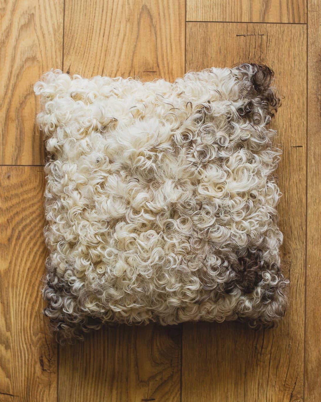 Nordvek Spanish Sheepskin Cushion 9016-100 Dark On Wooden Floor