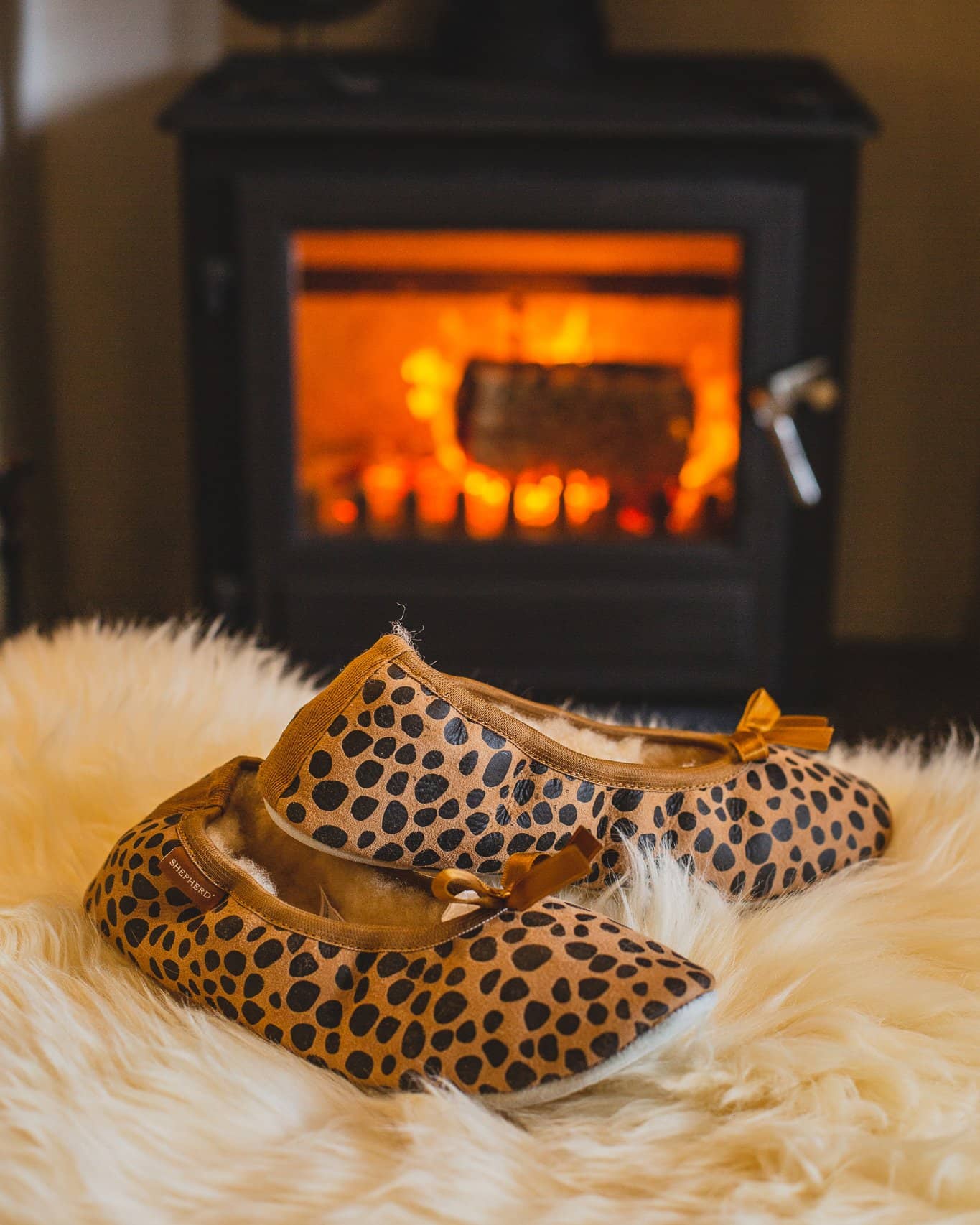 shepherd womens sheepskin slippers SAGA leopard pair in front of fire